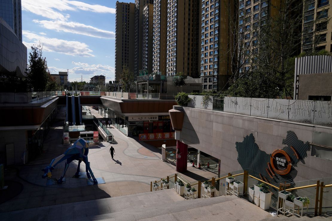 A man walks through a quiet Evergrande city plaza past a map showing Evergrande development projects and its apartment buildings in Beijing, Tuesday, Sept. 21, 2021. Global investors are watching nervously as the Evergrande Group, one of China's biggest real estate developers, struggles to avoid defaulting on tens of billions of dollars of debt, fueling fears of possible wider shock waves for the Chinese financial system. (AP Photo/Andy Wong)